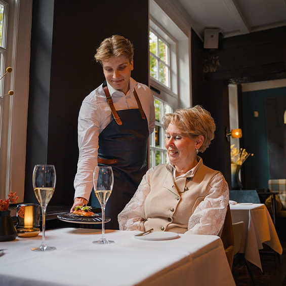 Medewerker restaurant brengt eten aan vrouw